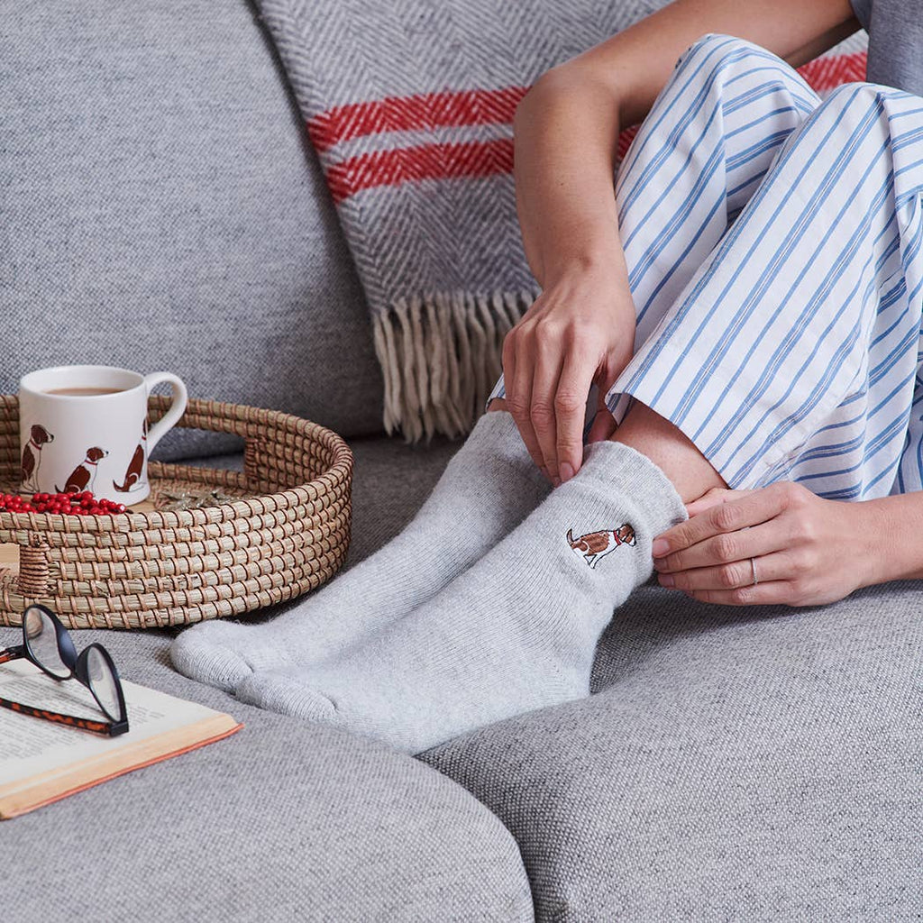Person wearing light grey socks with a embroidered dog, woollen cosy socks